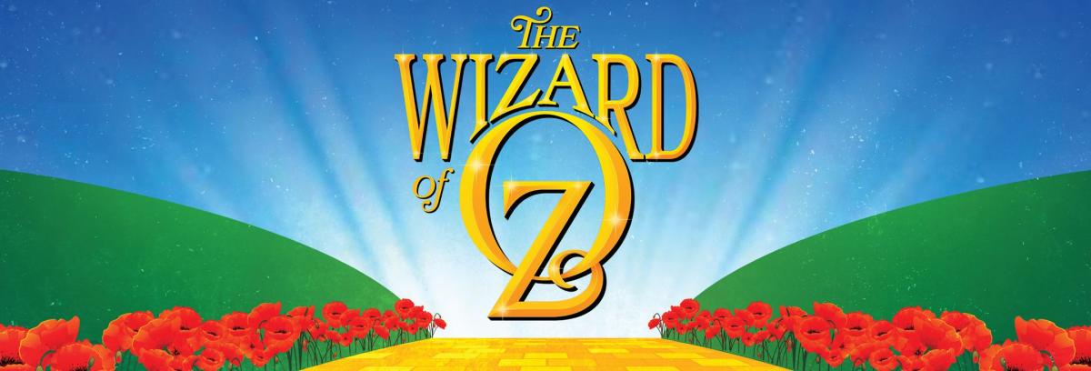 Image shows the words Wizard of Oz above a yellow brick road lined with red poppy flowers. 